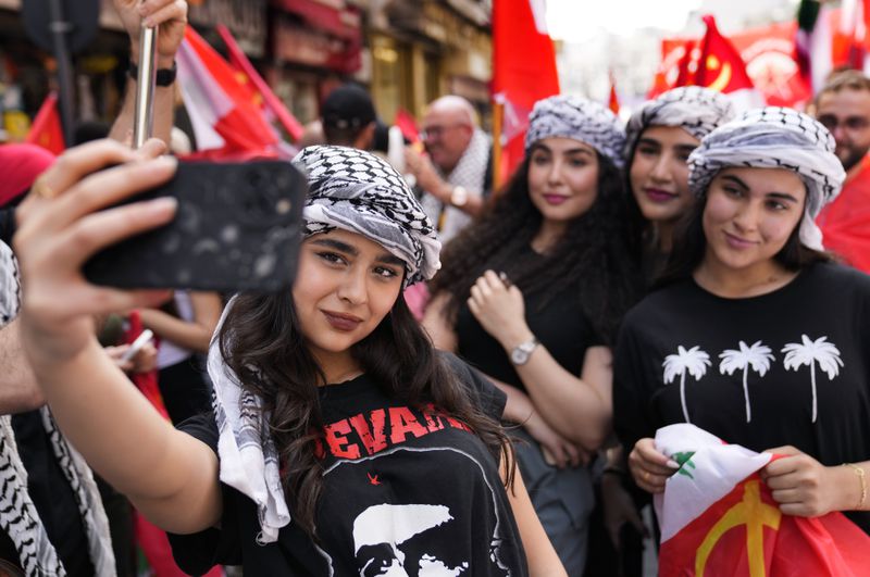 Supporters of the Lebanese Communist party, take selfie, as they march during a demonstration to mark International Labor Day or May Day, in Beirut, Wednesday, May 1, 2024. Despite the tense situation and ongoing clashes on Lebanon's border with Israel over the past seven months, hundreds of protesters marched through Beirut's streets to mark International Workers' Day. (AP Photo/Hussein Malla)