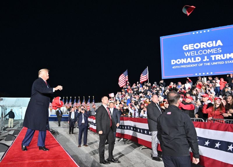 March 26, 2022 Commerce - Former former President Donald Trump throws hats as he enters the stage during a rally for Georgia GOP candidates at Banks County Dragway in Commerce on Saturday, March 26, 2022. (Hyosub Shin / Hyosub.Shin@ajc.com)