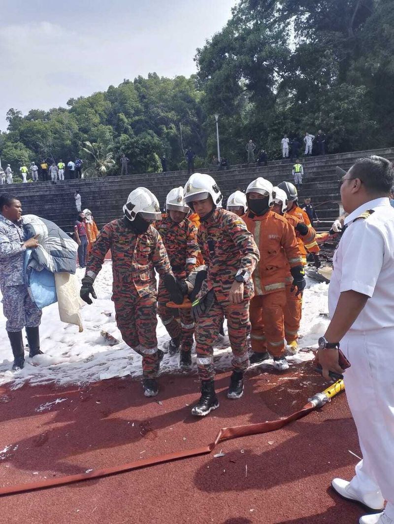 In this photo released by Fire & Rescue Department of Malaysia, fire and rescue department move out a body from the crash site of two helicopter in Lumur, Perak state, Monday, April 23, 2024. Malaysia's navy says two military helicopters collided and crashed during a training session, killing all 10 people on board. (Terence Tan/Ministry of Communications and Information via AP)