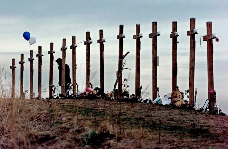 FILE - A woman stands among crosses posted on a hill above Columbine High School in Littleton, Colo., in remembrance of the people who died during a school shooting on April 20, 1999. Twenty-five years later, The Associated Press is republishing this story about the attack, the product of reporting from more than a dozen AP journalists who conducted interviews in the hours after it happened. The article first appeared on April 22, 1999. (AP Photo/Eric Gay, File)