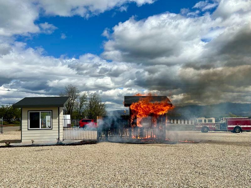 A building constructed using traditional materials and landscaping is engulfed by flames during a burn demonstration at the National Interagency Fire Center in Boise, Idaho, Monday, April 29, 2024. The building on the right was also exposed to flames during the demonstration, but it was built using fire-resistant materials and was mostly protected from damage. (AP Photo/Rebecca Boone)
