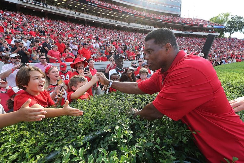 091121 Athens: Georgia U.S. Senate Candidate Herschel Walker gives fans along the hedges five before he is introduced as a member of Georgia's 1980 National Championship team during half time ceremonies against UAB in a NCAA college football game on Saturday, Sept 11, 2021, in Athens.    “Curtis Compton / Curtis.Compton@ajc.com”