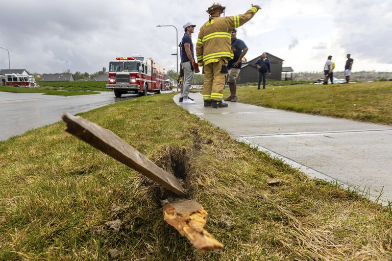 A piece of wood is embedded in the ground as firefighters assess the damages to houses after a tornado passed through the area near Omaha, Neb., on Friday, April 26, 2024. (Chris Machian/Omaha World-Herald via AP)