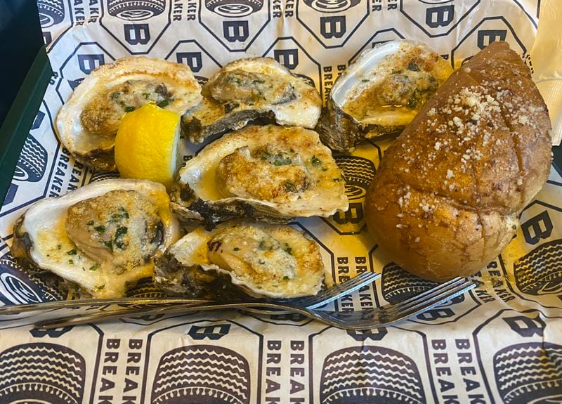 The charbroiled oysters at Breaker Breaker are drenched in garlic butter and melted Parmesan. Ligaya Figueras/ligaya.figueras@ajc.com