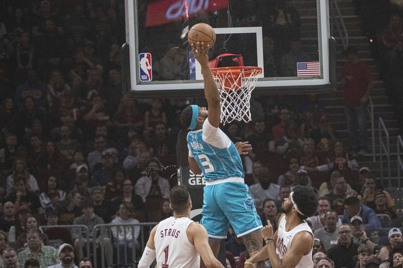 Charlotte Hornets' Marques Bolden (3) tips the ball as Cleveland Cavaliers' Max Strus (1) and Jarrett Allen, right, watch during the first half of an NBA basketball game in Cleveland, Sunday, April 14, 2024. (AP Photo/Phil Long)