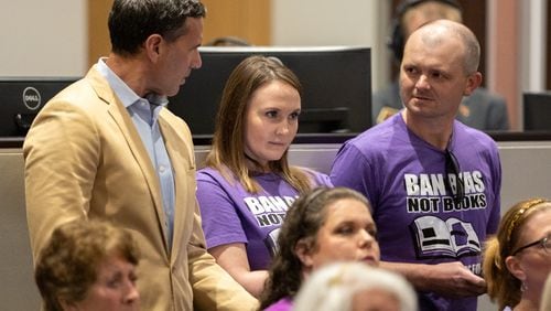 Teacher Katie Rinderle (center) and her attorneys Craig Goodmark (left) and Mike Tafelski (right) watch as the Cobb County school board prepares to vote on Rinderle’s case at a meeting in Marietta on Thursday, Aug. 17, 2023. The school board later voted to fire Rinderle, who read a book that challenges gender norms to fifth grade students. (Arvin Temkar/arvin.temkar@ajc.com)