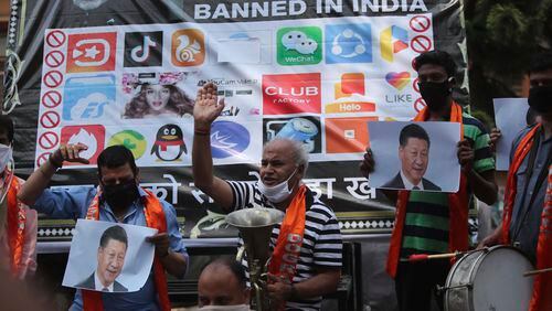 FILE- Activists of Jammu and Kashmir Dogra Front shout slogans against Chinese President Xi Jinping next to a banner showing the logos of TikTok and other Chinese apps banned in India during a protest in Jammu, India, July 1, 2020. (AP Photo/Channi Anand, File)