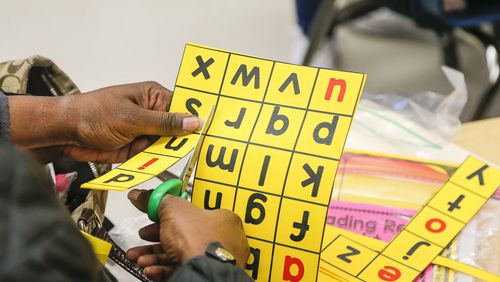 A first grade parent cuts out letters for at home learning with their child during an Academic Parent Teacher Teams meeting after school, Monday, January 21, 2020. Teachers encouraged parents to engage their students academically when they are away from the classroom in order to encourage continuous learning. (ALYSSA POINTER/ALYSSA.POINTER@AJC.COM)