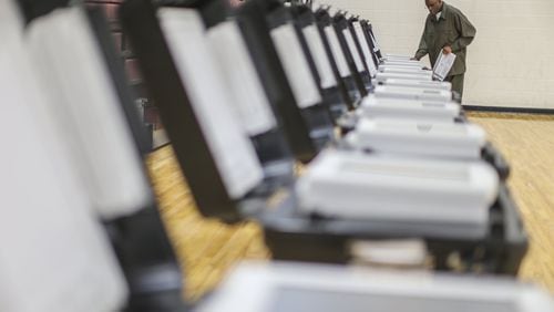 Poll manager Melvin Davis Jr. prepare voting machines in Fulton County. JOHN SPINK /JSPINK@AJC.COM AJC FILE PHOTO