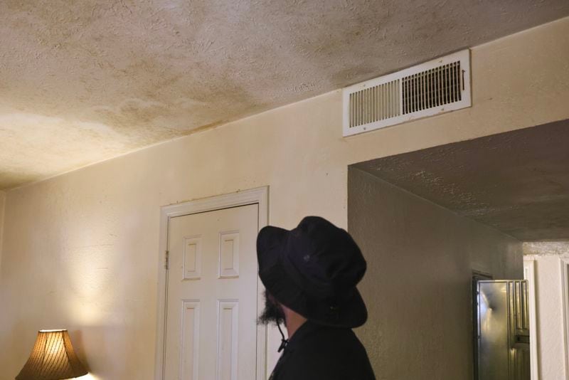 Senior Code Enforcement Officer Tyonne English looks up at mold and mildew on the ceiling of a Woodland Heights unit in July. The inspection by Atlanta's Safe and Secure Housing program took place after more than a decade of disrepair and violence at the complex, which was previously named Rolling Bends. (Natrice Miller/natrice.miller@ajc.com)