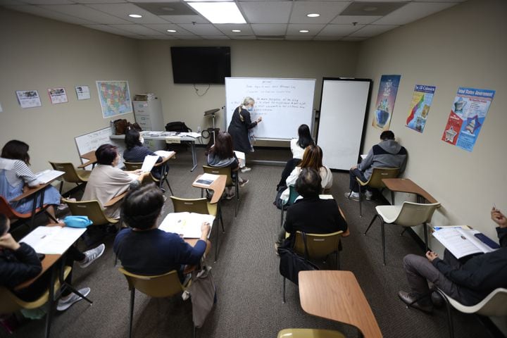 Third-level teacher Carolyn Wicher writes on the board during a class at Center of Pan American Services on  Nov. 11, 2021. (Miguel Martinez for The Atlanta Journal-Constitution)