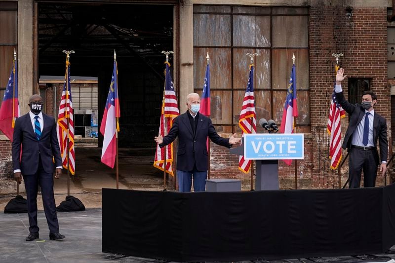 Flanked by U.S. Democratic Senate candidates the Rev. Raphael Warnock, left, and Jon Ossoff, right, President-elect Joe Biden gestures to the crowd at the end of a drive-in rally at Pullman Yard on Dec.15, 2020, in Atlanta. (Drew Angerer/Getty Images/TNS)