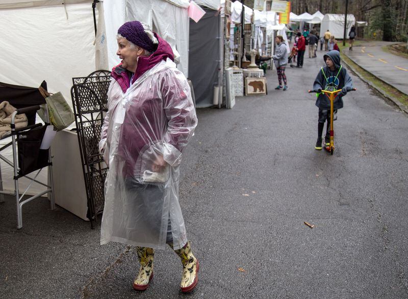 Artist Bailey Jack tries to stay warm and dry during the Brookhaven Cherry Blossom Fest on Sunday, March 25, 2018. STEVE SCHAEFER / SPECIAL TO THE AJC