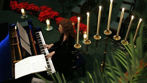 Pianist Brandi Williams plays surrounded by Christmas decorations including several poinsettias during the prelude to the Christmas Eve Communion Service at Mount Carmel Christian Church Wednesday night in Stone Mountain, Ga., December 24, 2008. This is the same church that vandals, earlier this December, destroyed the manger of their drive-through living Nativity scene. JASON GETZ / jgetz@ajc.com