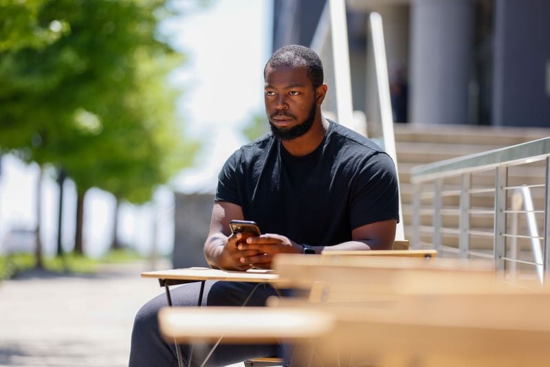 Alexander Burt, senior at Morehouse College, is seen using his cell phone just outside the campus on Wednesday, April 24, 2024. The college is preparing to welcome President Biden, who will deliver a speech during the commencement ceremony on May 19.
(Miguel Martinez / AJC)