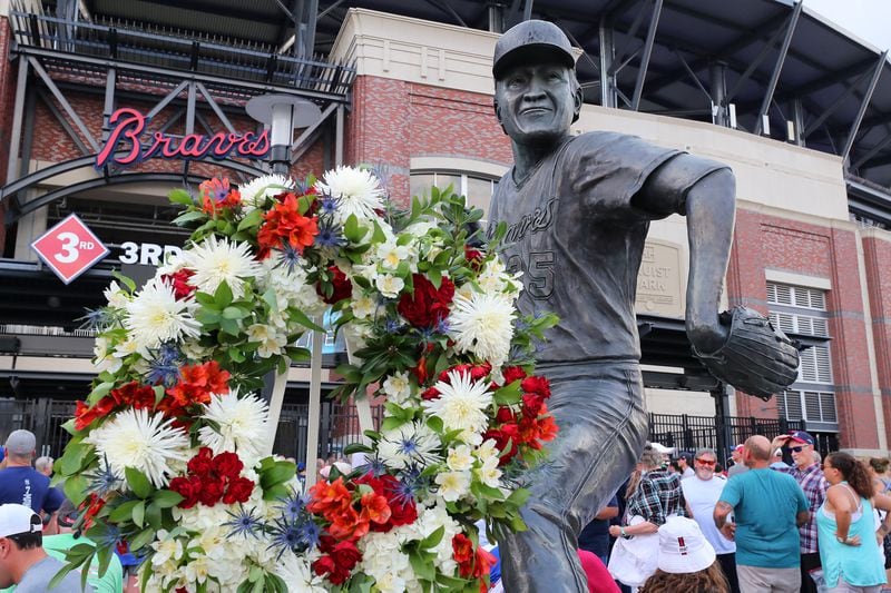 A statue of Phil Niekro outside Truist Park is adorned with flowers.
