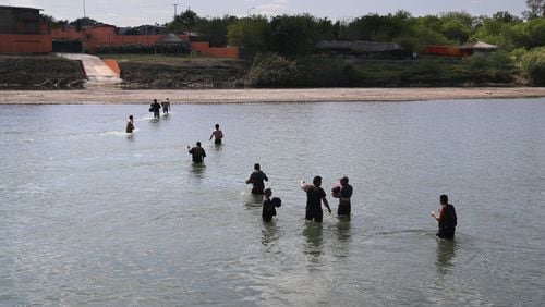 ROMA, TX : A group of undocumented immigrants wade across the Rio Grande River at the U.S.-Mexico border on March 14, after being turned back by U.S. Border Patrol agents. (Photo by John Moore/Getty Images)