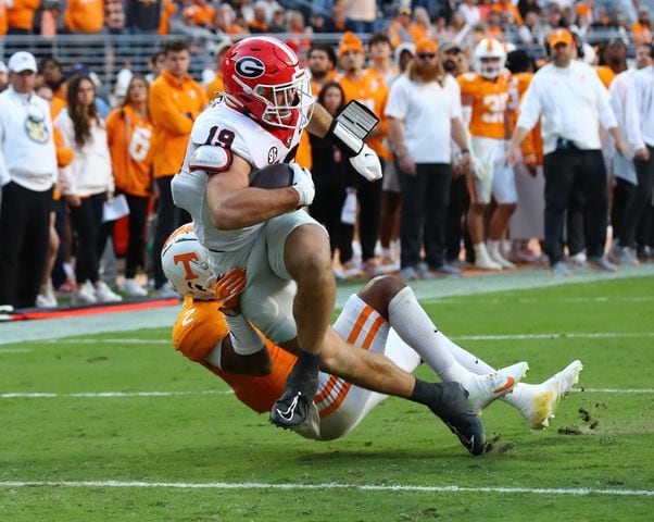 Georgia tight end Brock Bowers powers his way into the endzone past Tennessee defensive back Jaylen McCollough to take a 24-7 lead during the second quarter in a NCAA college football game on Saturday, Nov. 18, 2023, in Knoxville.  Curtis Compton for the Atlanta Journal Constitution