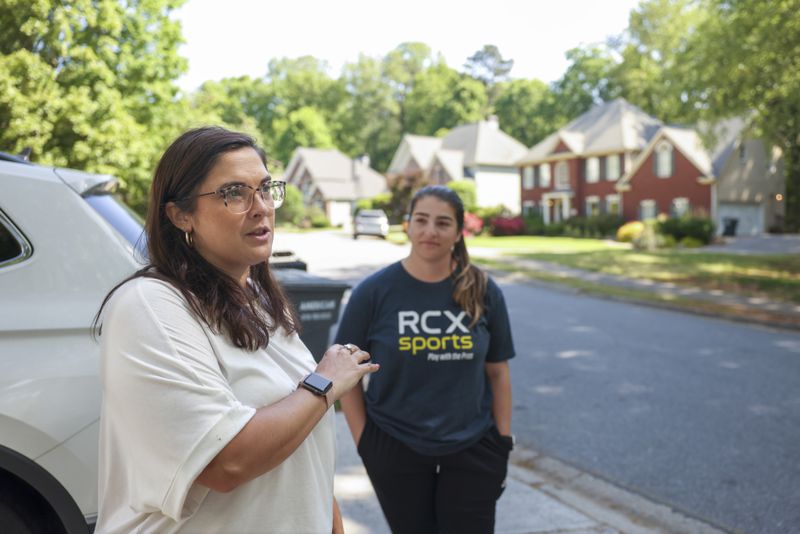 Brittany Peterson, left, and Jillian Scelsi stand across the street from the Powder Springs home where a man was arrested for illegally squatting after it became vacant. (Jason Getz / AJC)
