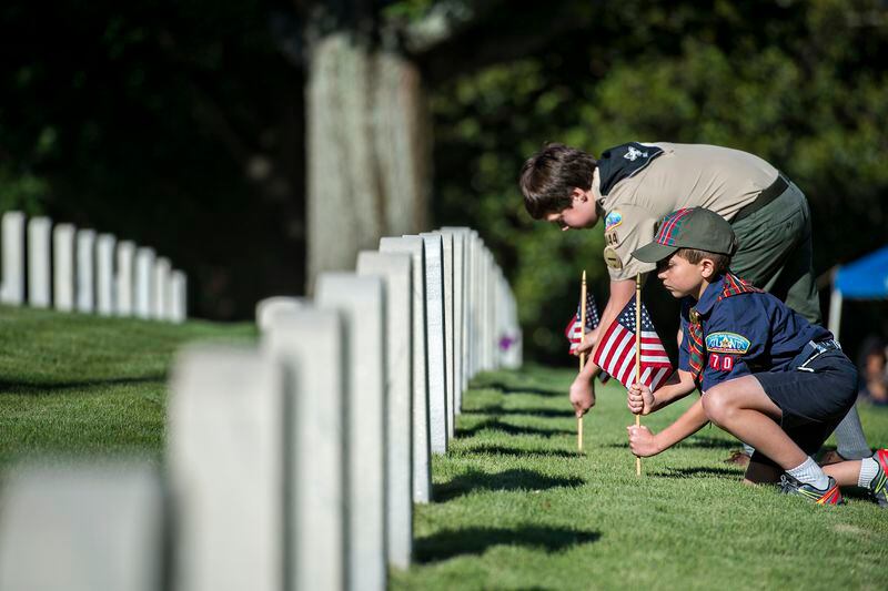 Bennett Robertson (right) and Paul Thornburgh plant flags at two of the graves in the Marietta National Cemetery on Memorial Day. The Boy Scouts of America's national leadership is about to vote on lifting a ban on gay leaders. JONATHAN PHILLIPS / SPECIAL