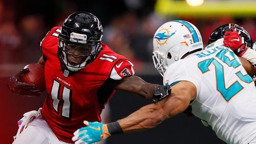 Falcons wide receiver Julio Jones stiff-arms Nate Allen of the Dolphins at Mercedes-Benz Stadium last Sunday in Atlanta.