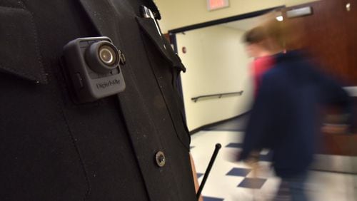 Officer Tate Ledford of the Cobb County School District Police Department, wearing a body camera, conducts a routine check at Wheeler High School in Marietta. Clayton, Cobb and Gwinnett Counties are among the school districts whose officers wear the cameras. Officers in Atlanta, DeKalb and Fulton do not. DeKalb is looking into buying cameras for its officers, a spokesman says. HYOSUB SHIN / HSHIN@AJC.COM