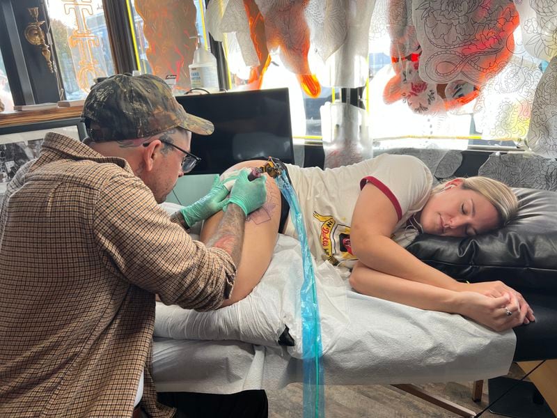 Joseph Fessman, owner of Yellow Bird Tattoo, gives Lauren Clark of Richmond, Virginia, a Duke's Mayo-inspired tattoo.