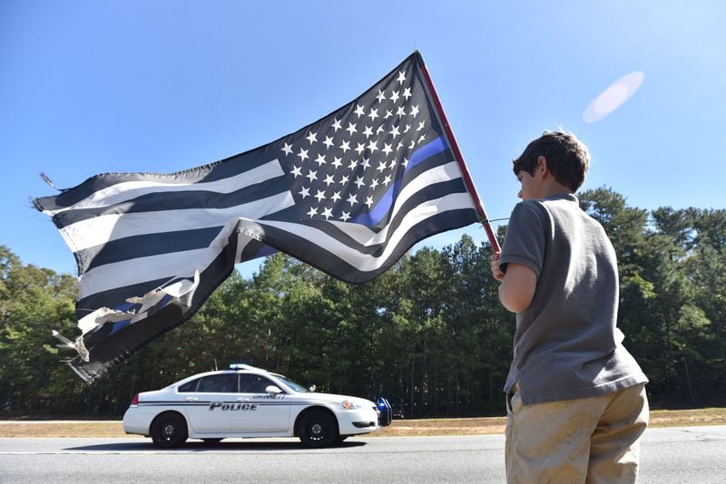 October 24, 2018 Lawrenceville -  Peyton Williams, 11, holds a flag to show his respect during the procession of  slain Gwinnett County police officer Antwan Toney outside 12Stone Church on Buford Drive on Wednesday, October 24, 2018. Gwinnett County police officer Antwan Toney, 30, was shot and killed Saturday while responding to a call in the Snellville area. The California native worked for nearly three years for the Gwinnett police department. A funeral was hold at 11 a.m. Wednesday at 12Stone Church, 1322 Buford Drive in Lawrenceville. HYOSUB SHIN / HSHIN@AJC.COM