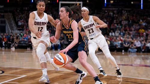 Indiana Fever's Caitlin Clark (22) goes to the basket against Atlanta Dream's Nia Coffey (12) and Aerial Powers (23) during the second half of a WNBA preseason basketball game Thursday, May 9, 2024, in Indianapolis. Clark scored 12 and the Fever won 83-80. (AP Photo/Darron Cummings)