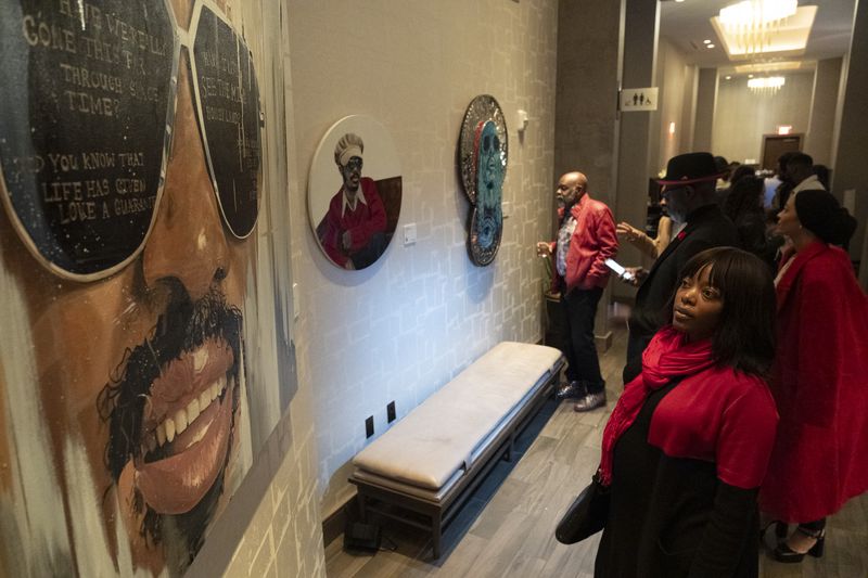 Stacey Chavis views takes in a painting during Art Melanated’s Stevie Wonder exhibit opening at Thompson Atlanta in Buckhead on Friday, Feb. 2, 2024.   (Ben Gray / Ben@BenGray.com)