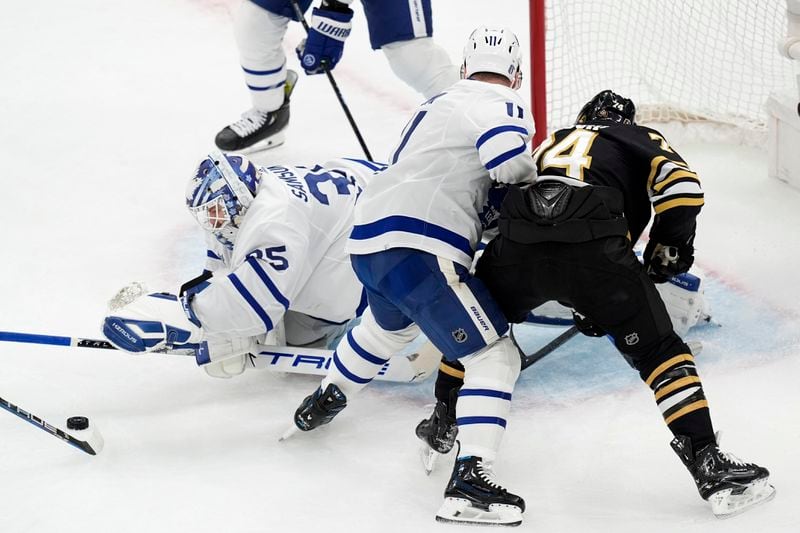 Toronto Maple Leafs' Ilya Samsonov (35) reaches for the puck as Max Domi (11) defends against Boston Bruins' Jake DeBrusk (74) during the first period of Game 7 of an NHL hockey Stanley Cup first-round playoff series, Saturday, May 4, 2024, in Boston. (AP Photo/Michael Dwyer)