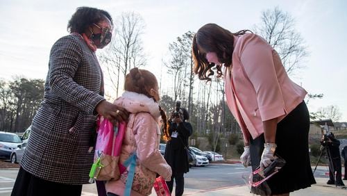 John R. Lewis Elementary School principal LaShawn McMillan, right, greets students as their dropped off for the first day of in-person learning at John R. Lewis Elementary School in Atlanta on March 9, 2021. The DeKalb County School District said it will no longer require students and staff to wear masks. (Alyssa Pointer / Alyssa.Pointer@ajc.com)