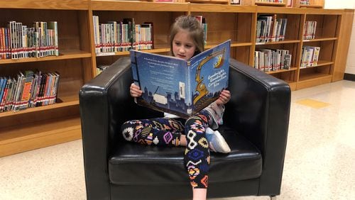 First-grader Lillian Boggs dives into a book by Sherri Rinker, an author who recently paid a virtual visit to Indian Knoll Elementary in Canton.