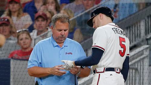Braves athletic trainer Jim Lovell inspects Freddie Freeman's injury Wednesday night, but can't make it better. (AP Photo/John Bazemore)