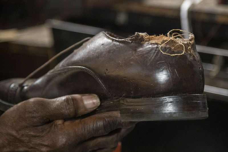 Joe Jordan, 82, owner of Cato Shoe Repair, shows off a shoe he will repair at his store in Atlanta. The owner of the shoes told Jordan that a dog chewed the back of one. (ALYSSA POINTER / ALYSSA.POINTER@AJC.COM)