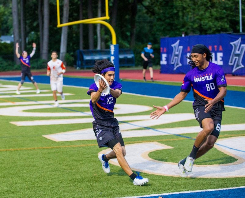 The Hustle, Atlanta's American Ultimate Disc League team, scores with Matt Smith (left), #12, catching the disc with teammate Antoine Davis, #80, ready to move in if needed against Philadelphia at St. Pius X High School Field on Saturday, June 26, 2021. (Jenni Girtman for The Atlanta Journal-Constitution)