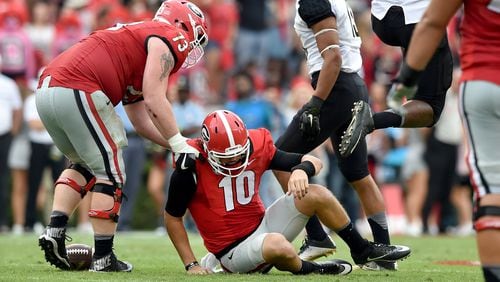 Georgia quarterback Jacob Eason is helped up by teammate Greg Pyke after he was sacked to bring up 4th and 15 in the 3rd quarter Saturday. The Bulldogs lost to Vanderbilt 17-16 on at Sanford Stadium. (Brant Sanderlin bsanderlin@ajc.com)