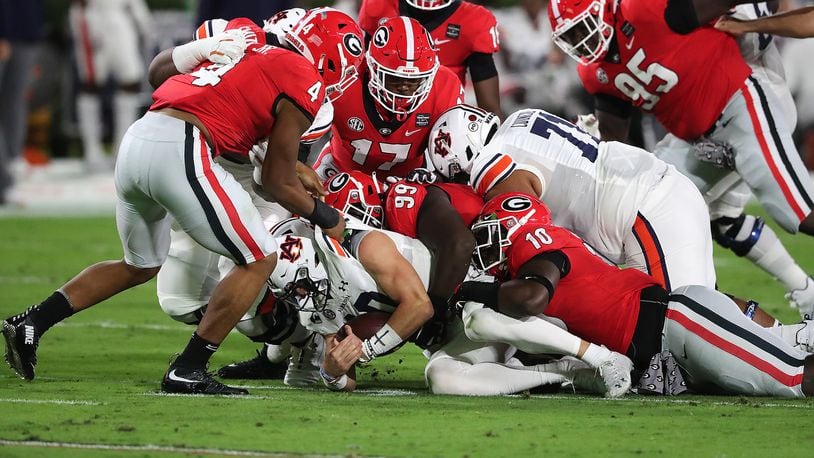 Georgia defenders pile on Auburn quarterback Bo Nix for no gain during the first quarter of Saturday's game in Athens. Georgia kept Auburn out of the end zone and only allowed a pair of field goals in the 27-6 victory. (Curtis Compton/AJC)