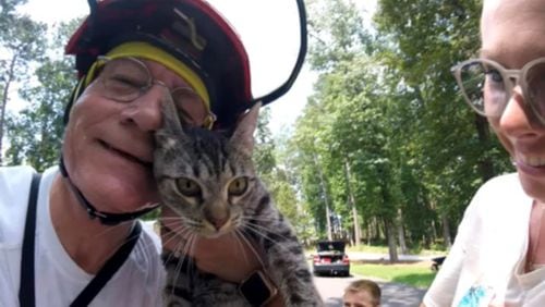 Normer Adams, a retired child advocate, with a cat and its happy owner after rescuing the animal from a tree in 2021.
