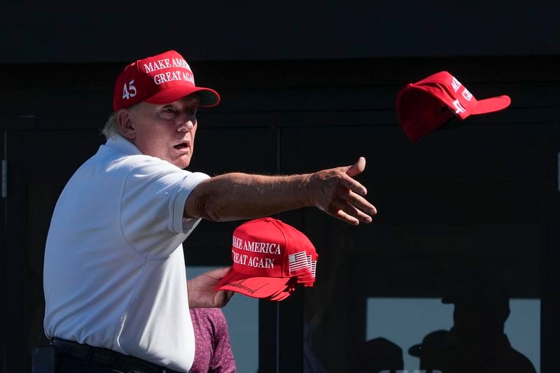 FILE - Former President Donald Trump throws autographed hats to the crowd during the final round of the Bedminster Invitational LIV Golf tournament in Bedminster, N.J., Sunday, Aug. 13, 2023. He's a criminal defendant, a businessman and a politician. But to his most loyal supporters, Donald Trump will always be Mr. President. When it comes to signaling our political loyalities, language can be just as telling as a MAGA cap, offering a simple by subtle reminder of the false election claims that continue to reverberate online, as well as the polarization that has gripped our politics and divided our people.(AP Photo/Seth Wenig, File)