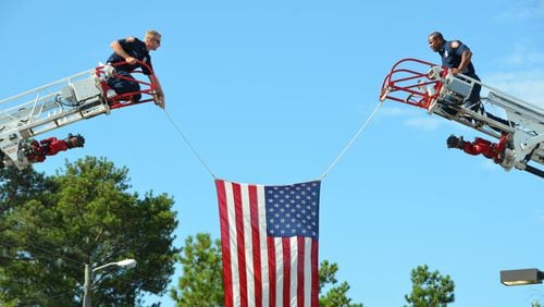 Firefighters hoist a flag at the Holy Innocents' service. Photo: Andre McIntosh