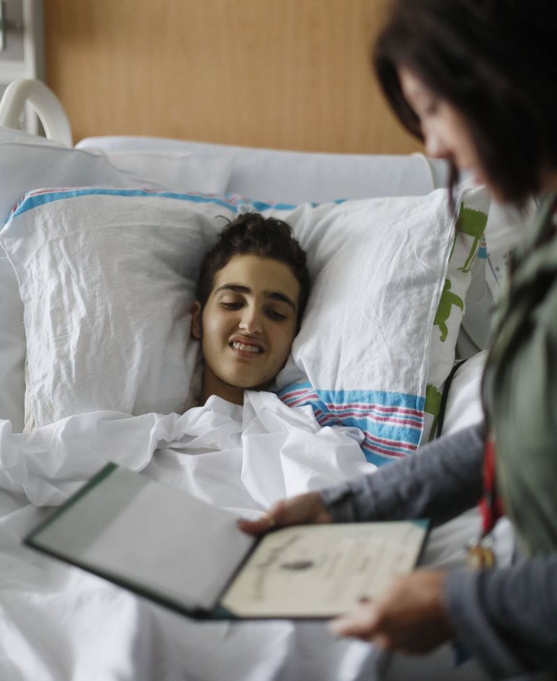 May 30, 2019 - Atlanta - Logan Droke gets a look at his high school diploma from Lori Pirtle, the hospital’s educational advocate for his unit. Pirtle has been working with Logan since he was 9 years old. Logan, 18, from Canton, facing his fourth battle with leukemia at Children’s Healthcare of Atlanta at Scottish Rite, is set to graduate from Creekview High School on Friday. Firefighters in two departments are rallying behind the teenager by raising money to help pay for treatments. Bob Andres / bandres@ajc.com