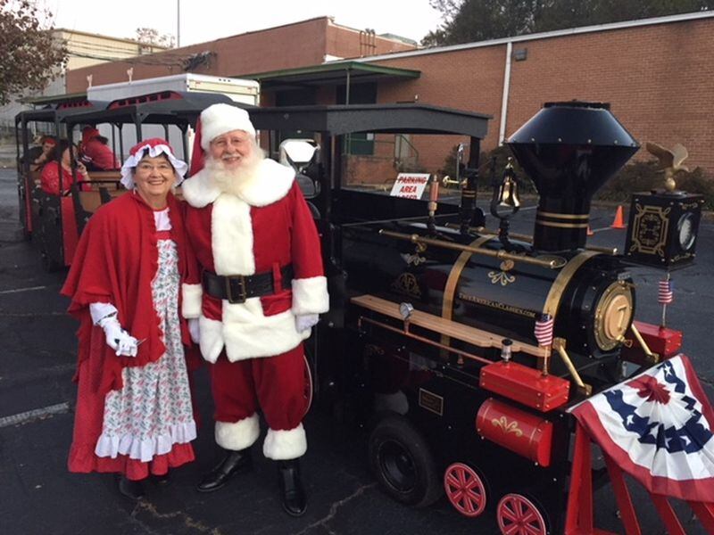 Stephanie and Phil Ludtke pose near the train that took them to the Gwinnett Historic Courthouse for the annual tree lighting ceremony, held Thanksgiving Day. CONTRIBUTED BY STEPHANIE LUDTKE