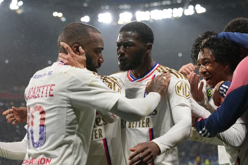 Lyon's Alexandre Lacazette, left, Ainsley Maitland-Niles, center, celebrate with Malick Fofana, right, who scored his side's third goal during a French League One soccer match between Lyon and Monaco at the Groupama stadium in Decines, outside Lyon, France, Sunday, April 28, 2024. (AP Photo/Laurent Cipriani)