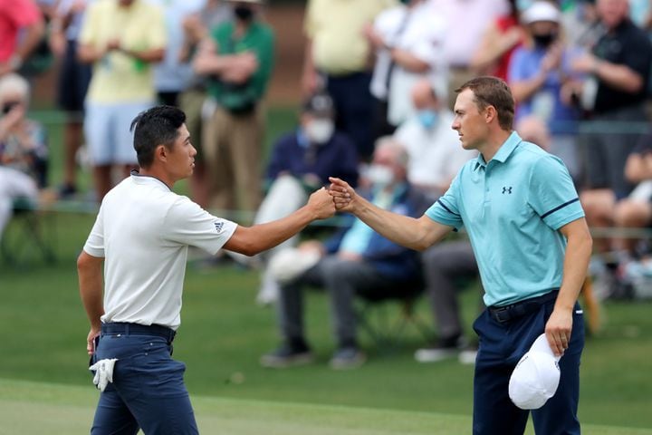 April 9, 2021, Augusta: Collin Morikawa, left, and Jordan Spieth fist bump as they finish their second round on the eighteenth green during the Masters at Augusta National Golf Club on Friday, April 9, 2021, in Augusta. Curtis Compton/ccompton@ajc.com