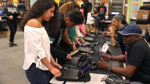 Technology has been on the forefront at the DeKalb County School District, as officials have worked to get devices to every student across the region. In September 2018, Cross Keys junior Lesly Chavez (center left) gets her Chromebook laptop logged in with help from DeKalb County Schools information technology employee Jeffrey Dotson (right) during the Chromebook distribution at Cross Keys High School. (JASON GETZ/SPECIAL TO THE AJC)