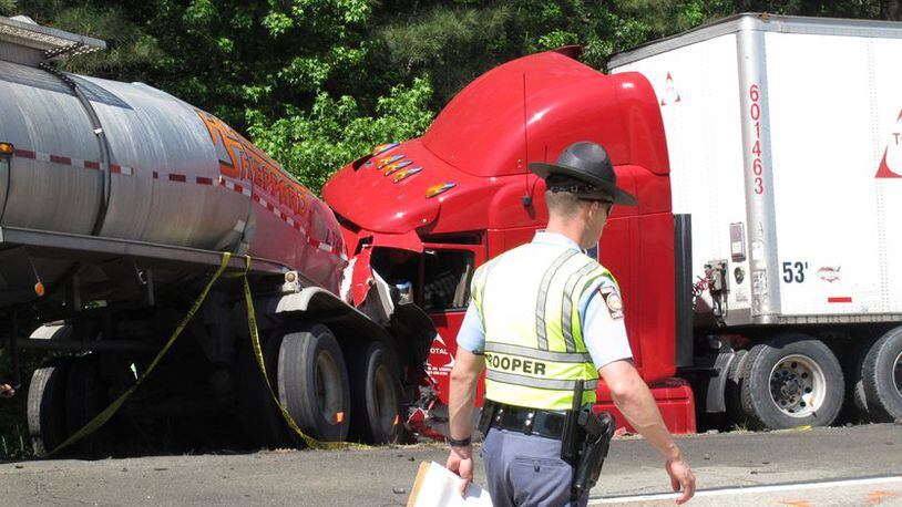 A Georgia state trooper works the scene of a deadly crash in which five people died and three others were injured Wednesday April 22, 2015, in Ellabelle, Ga., west of Savannah. The Georgia State Patrol said seven total vehicles, including two tractor trailers, were involved in the early morning collision on Interstate 16 about 20 miles west of Savannah. (AP Photo/Russ Bynum)