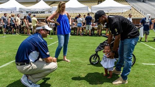 Georgia Tech quarterbacks/B-backs coach Craig Candeto (left) meets former Yellow Jackets A-back Tony Zenon's daughter Skyla (right), as Zenon and his wife, Abby, (center) looks on. They were taking part in Tech's Fan Day on Aug. 12, 2017 at Bobby Dodd Stadium. -- Danny Karnik/GT Athletics