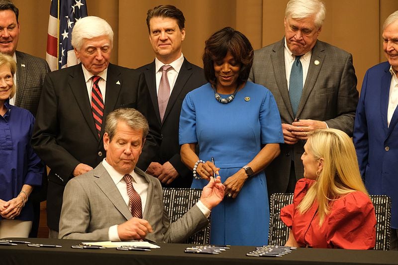 Gov. Brian Kemp hands a ceremonial pen to Morehouse Medical School President Valerie Montgomery Rice during a signing ceremony on Friday.