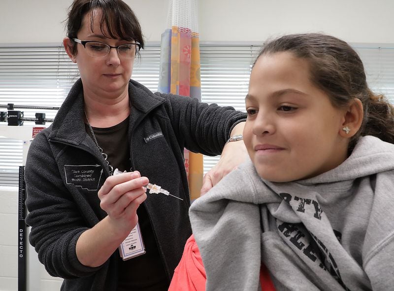 Kristen Earley, an RN at the Clark County Combined Health District, gives Braylinne Muhammad, 11, a flu shot Friday in the District’s offices. BILL LACKEY/STAFF